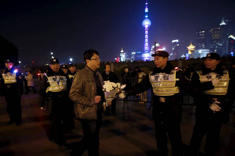 ชาวจีนในนครเซี่ยงไฮ้จำนวนหนึ่ง นำดอกไม้มาไว้อาลัยแก่ผู้เสียชีวิต ในเหตุเหยียบกันกลางงานฉลองปีใหม่ เมื่อปี 2015 ท่ามกลางการรักษาความปลอดภัยที่เข้มงวดกว่าเดิม (ภาพ: REUTERS)
